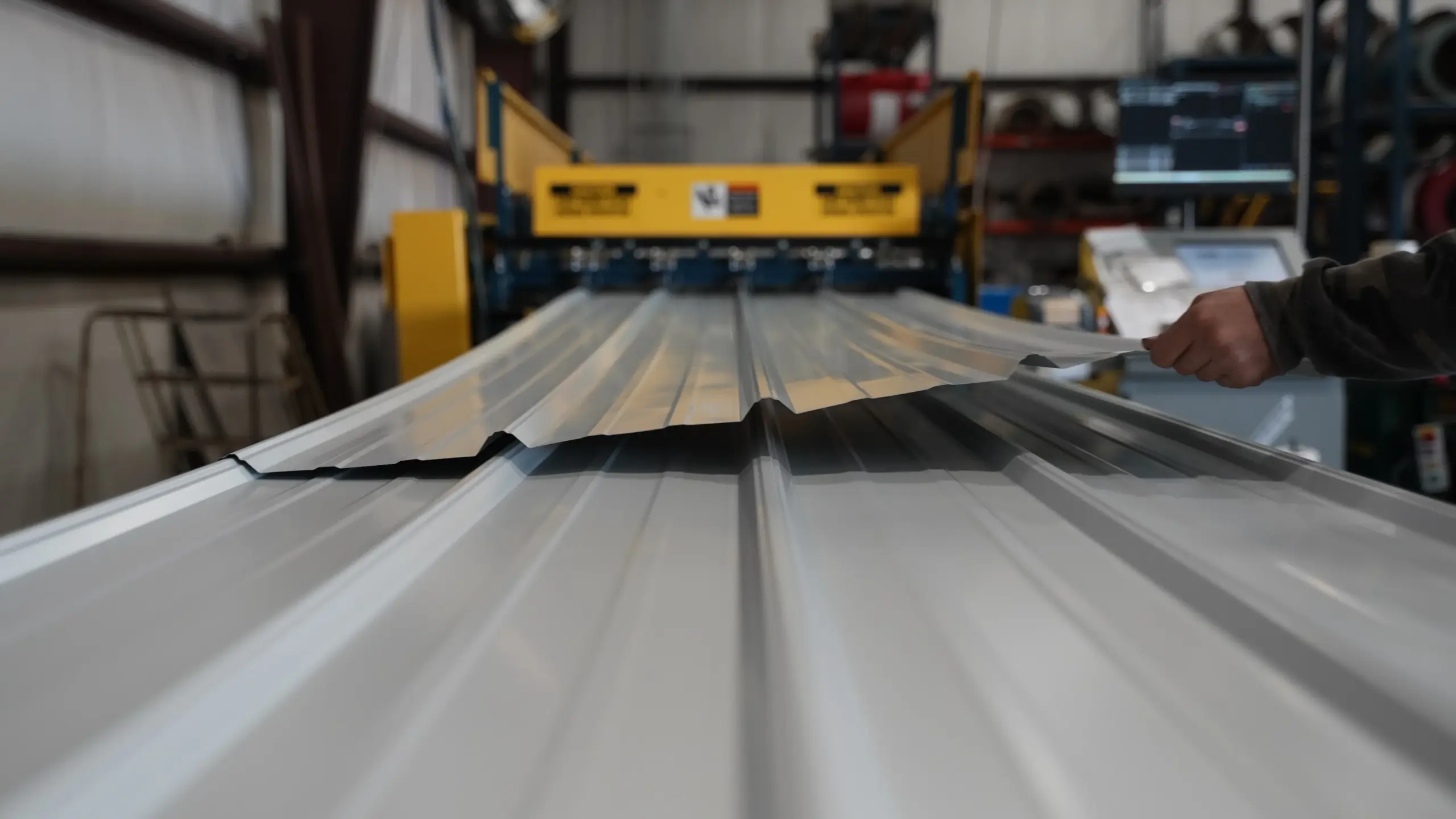gray metal panel coming out of a metal roller at the signature steel metal supply shop