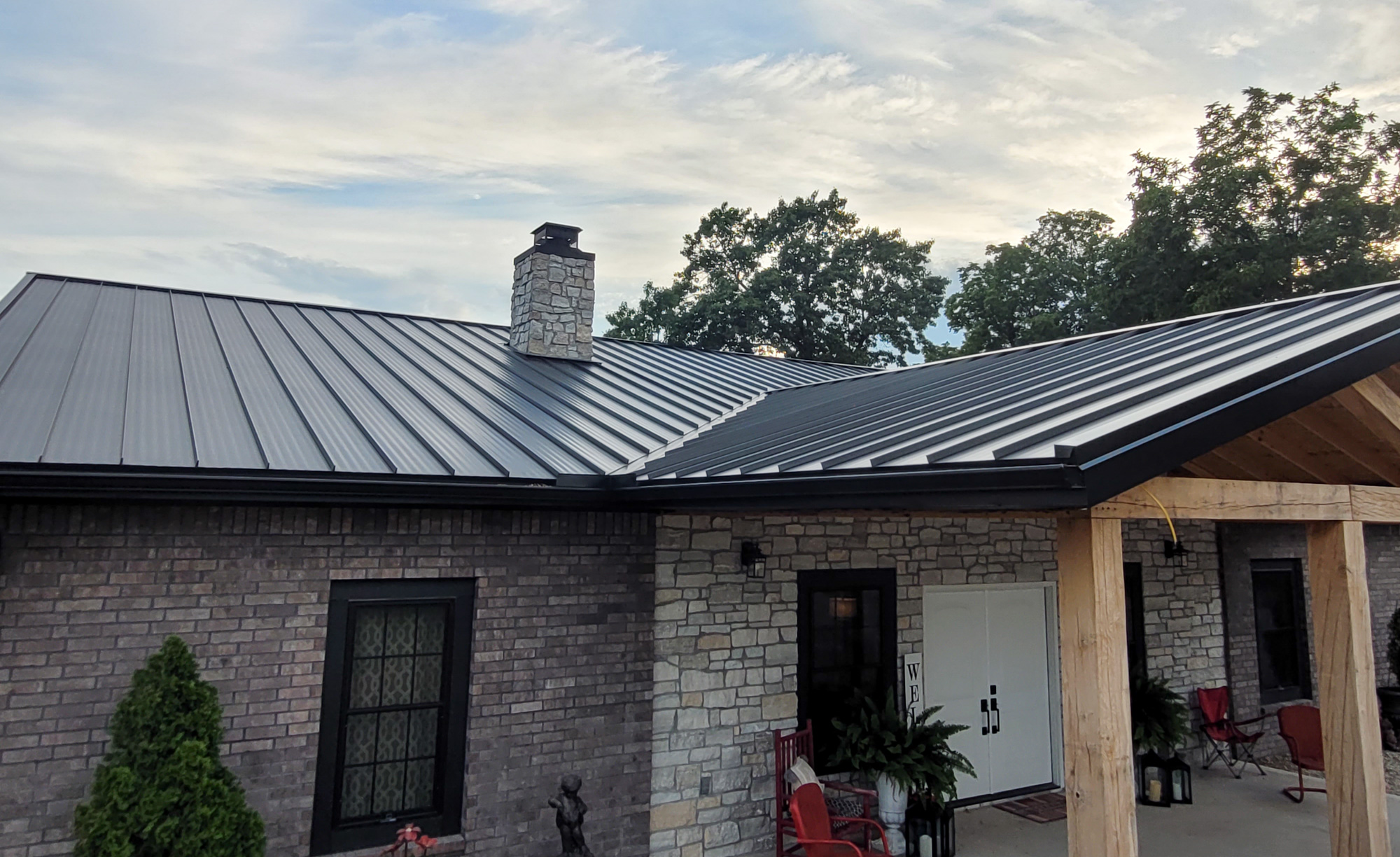 black standing seam metal roof in fayetteville arkansas with a rock chimney